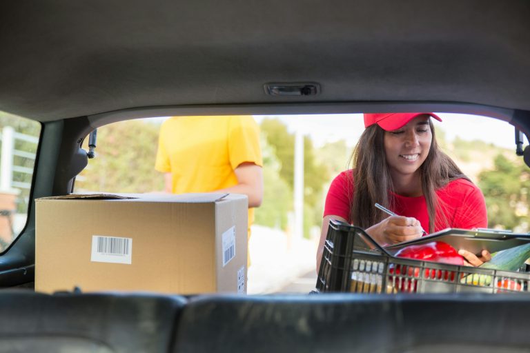 Efficient courier woman loading boxes into her car for delivery in Portugal.
